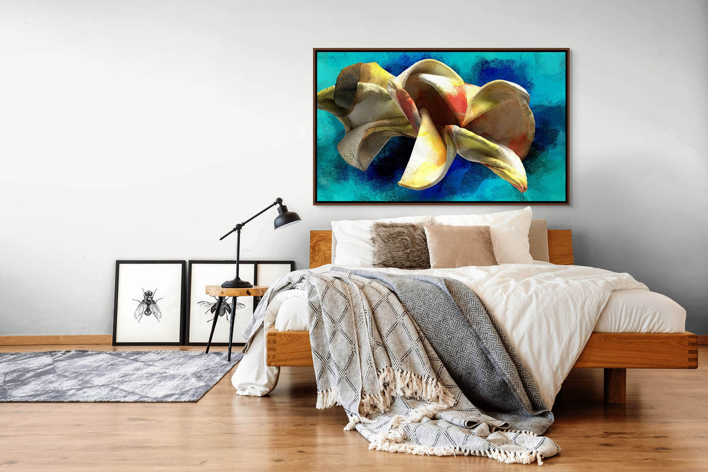 A modern bedroom showcases a wooden bed with white and beige bedding, complemented by a grey throw. Above is Blossoming Thought - Canvas Art, printed with eco-solvent inks. Two black-and-white insect giclee prints, a floor lamp, and hardwood flooring complete the cozy ambiance.