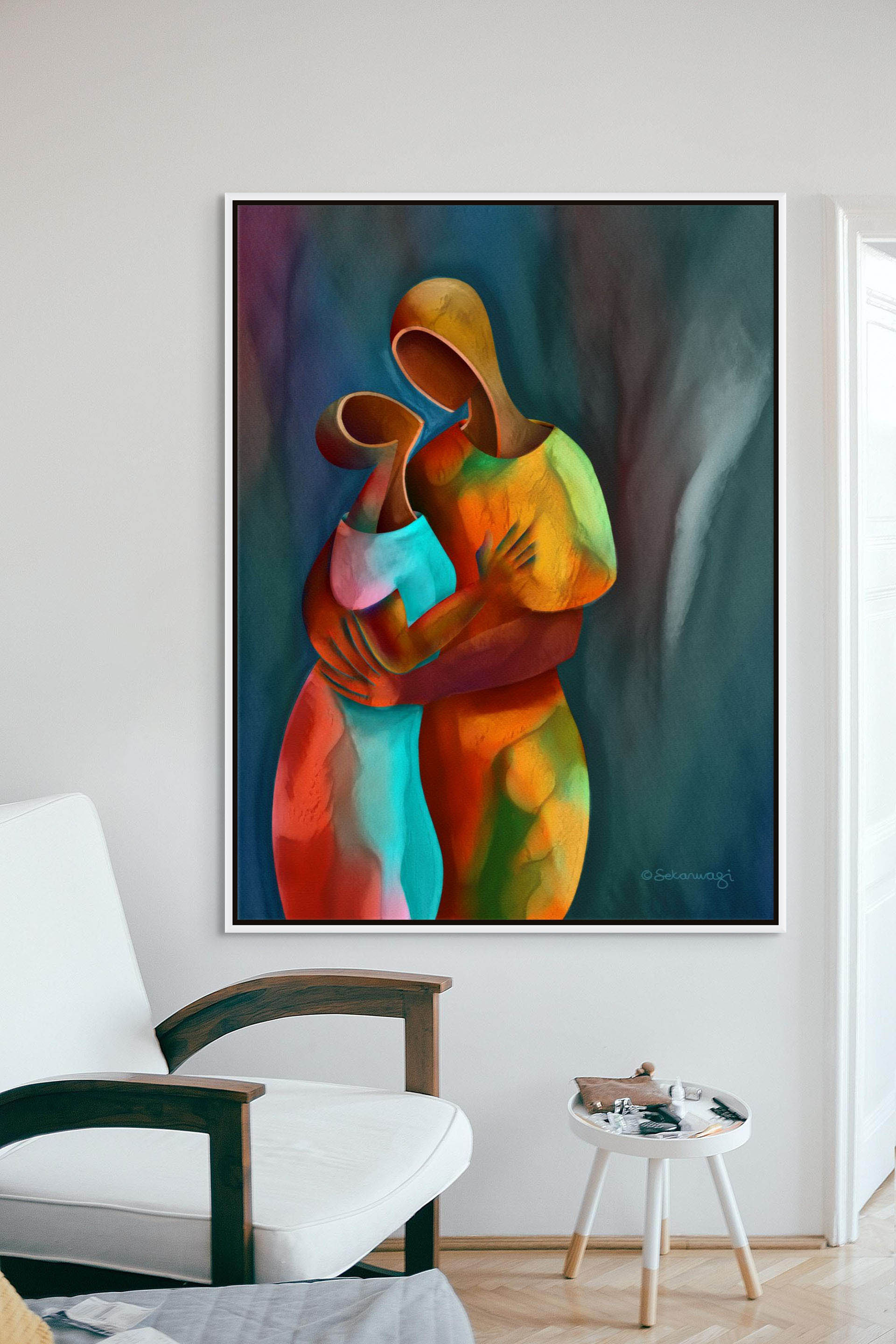 A modern room features Confidant - Canvas Art, an abstract painting of two hollowed out figures in vibrant orange, blue, and green. A white cushioned chair and a small round table complete the ready-to-hang setting.