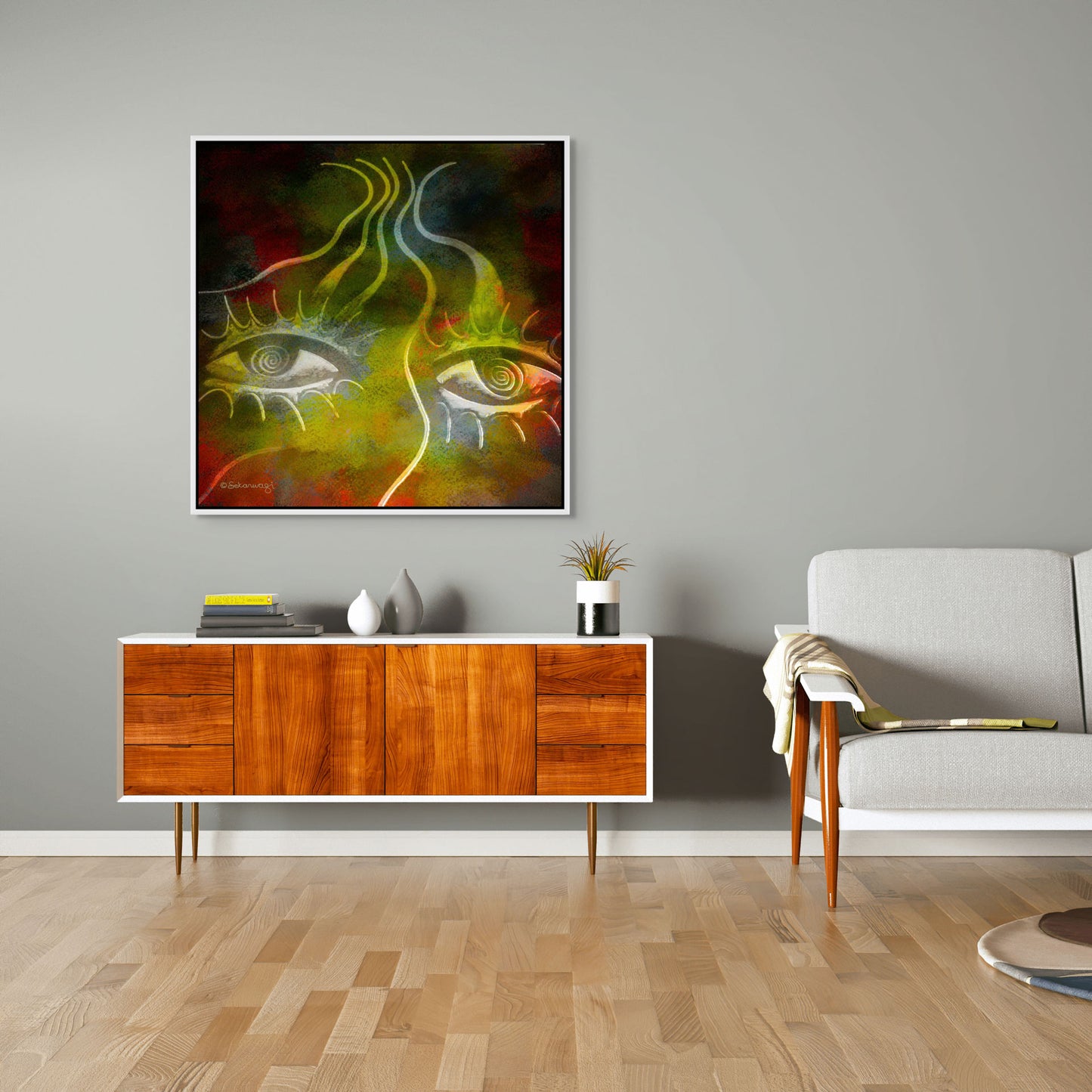 A modern living room features a mid-century wooden sideboard, a gray armchair, and Burning Desire - Contemporary African Minimalist Canvas Art on premium cotton canvas. The sideboard holds two vases and a book, while the light wood floor ties the space together harmoniously.
