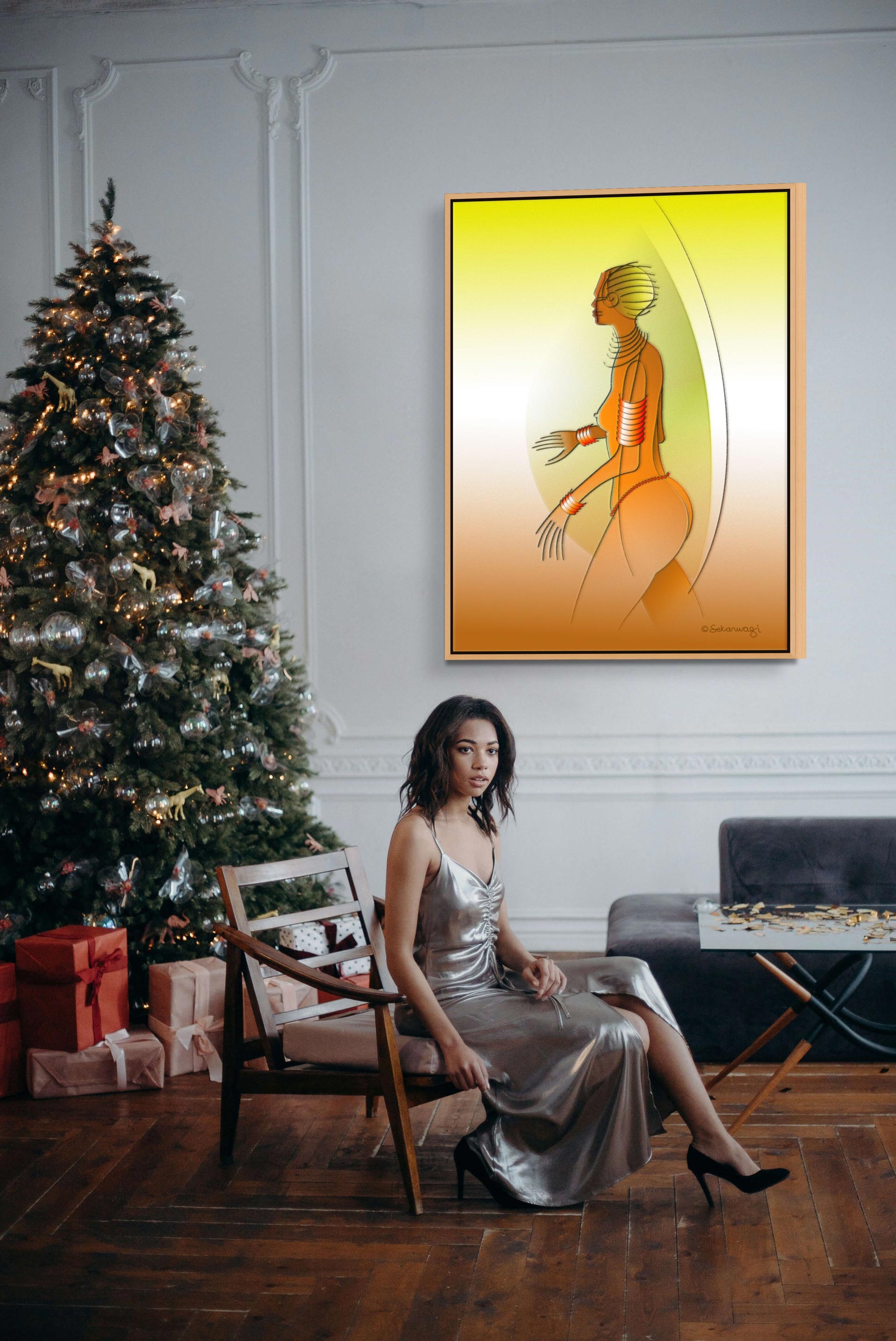 A person in a silver dress sits on a chair beside a decorated Christmas tree and presents. A colorful abstract painting, the Fantasy Woman - Contemporary African Expressionist Canvas Art Print, adorns the wall. The wooden floor enhances the dark couch, completing this magical scene.