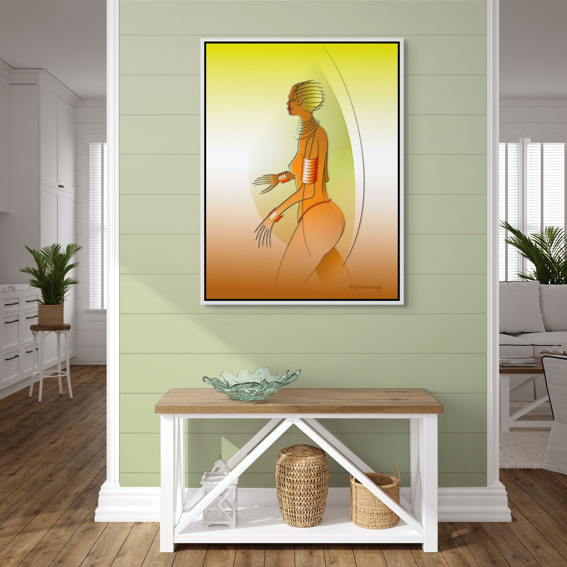 In a chic living room with light green walls, "Fantasy Woman", a colorful abstract  canvas art print  with a white floater frame hangs on the wall. A wooden console table displays an intricate glass bowl and woven baskets underneath tall windows that elegantly filter natural light.