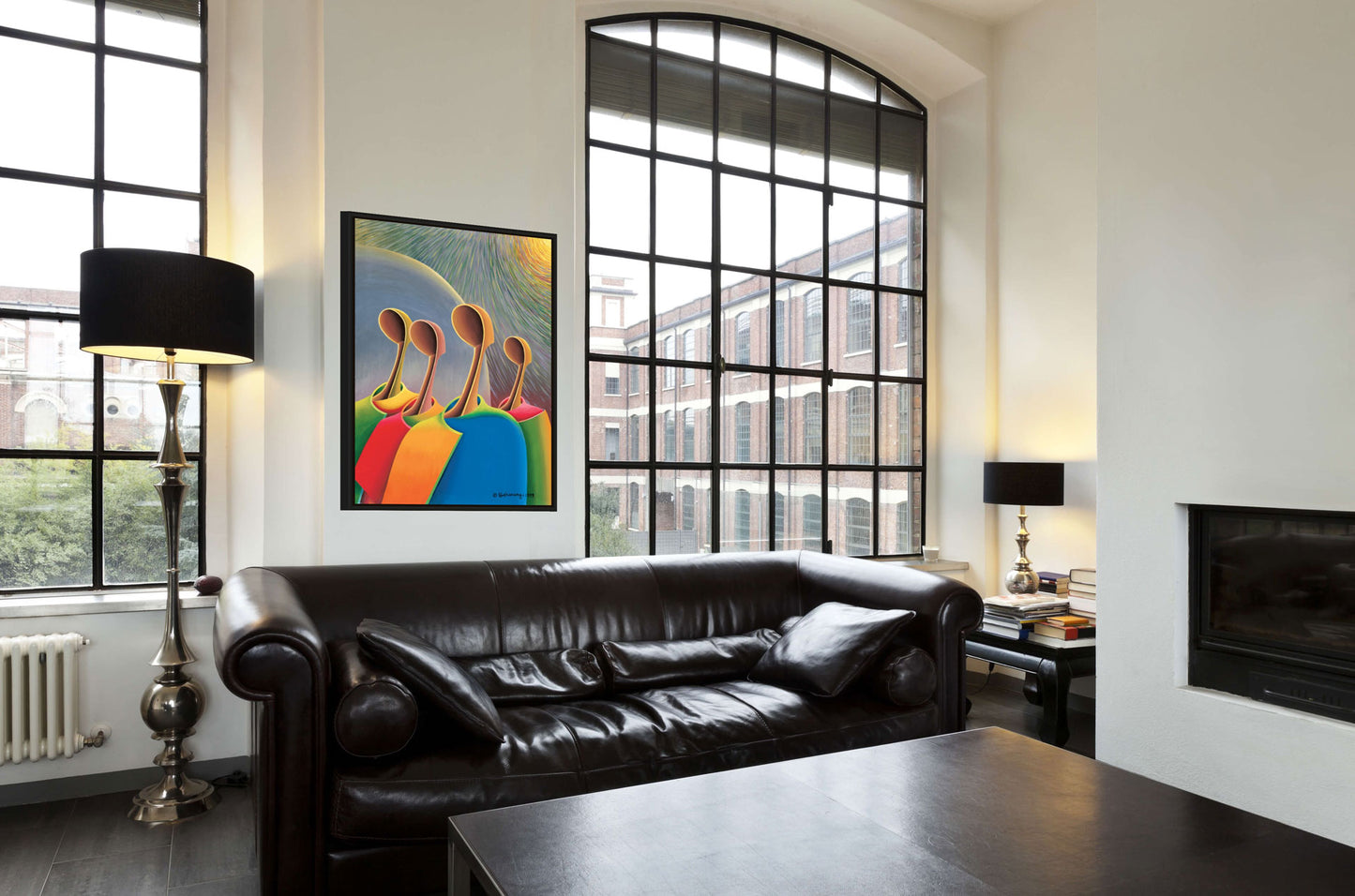 Modern living room featuring a black leather sofa by a large window with an urban view. The wall displays Great Expectations canvas art in gallery wrap style; a black lamp is beside the sofa, and a fireplace with books on a small table enhances the cozy atmosphere.