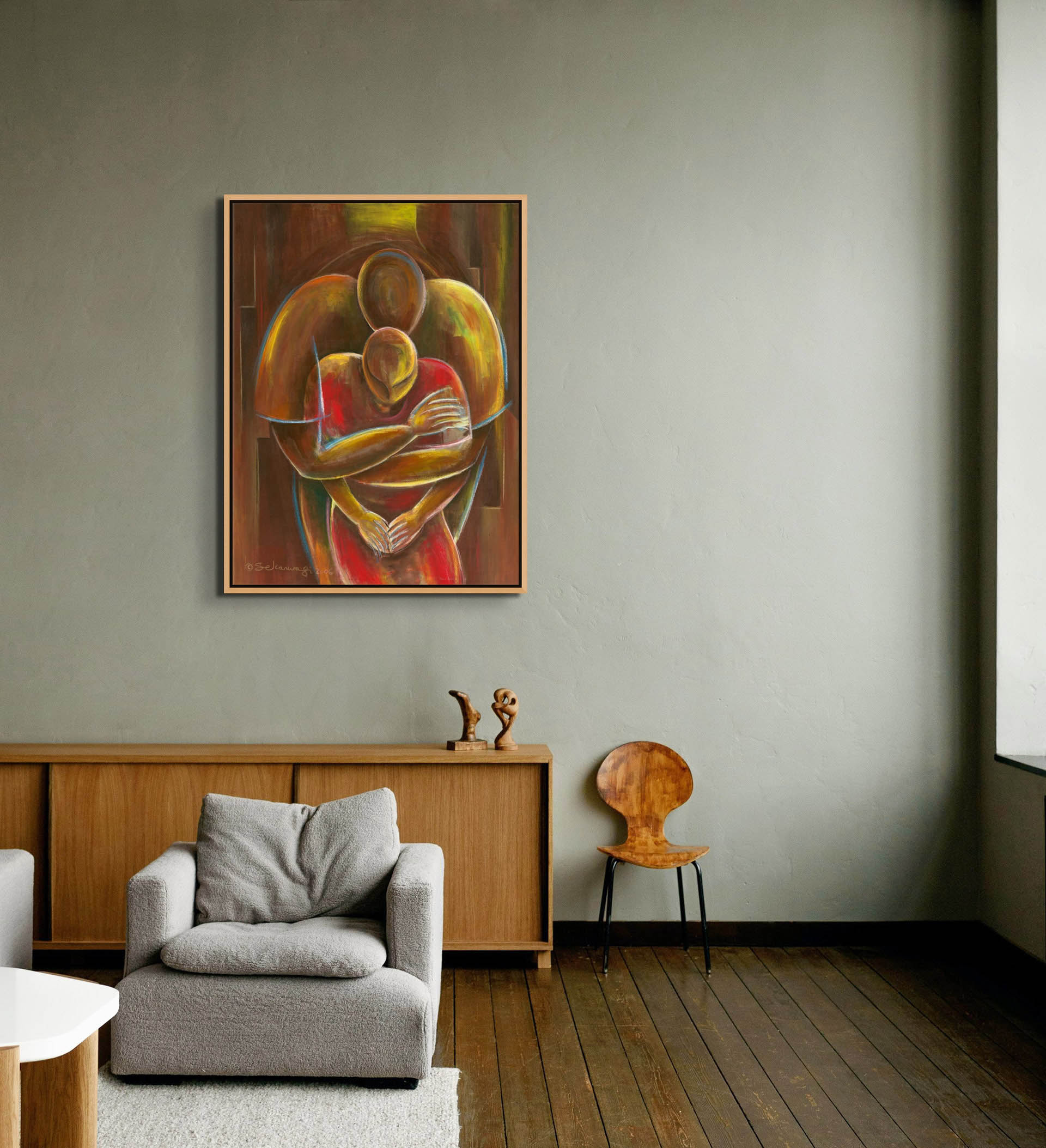 A modern living room with gray walls and wooden flooring features the Nurturing canvas art of two embracing figures above a wooden console. It includes a white sofa, small sculpture, and wooden chair, all displaying ready-to-hang elegance.