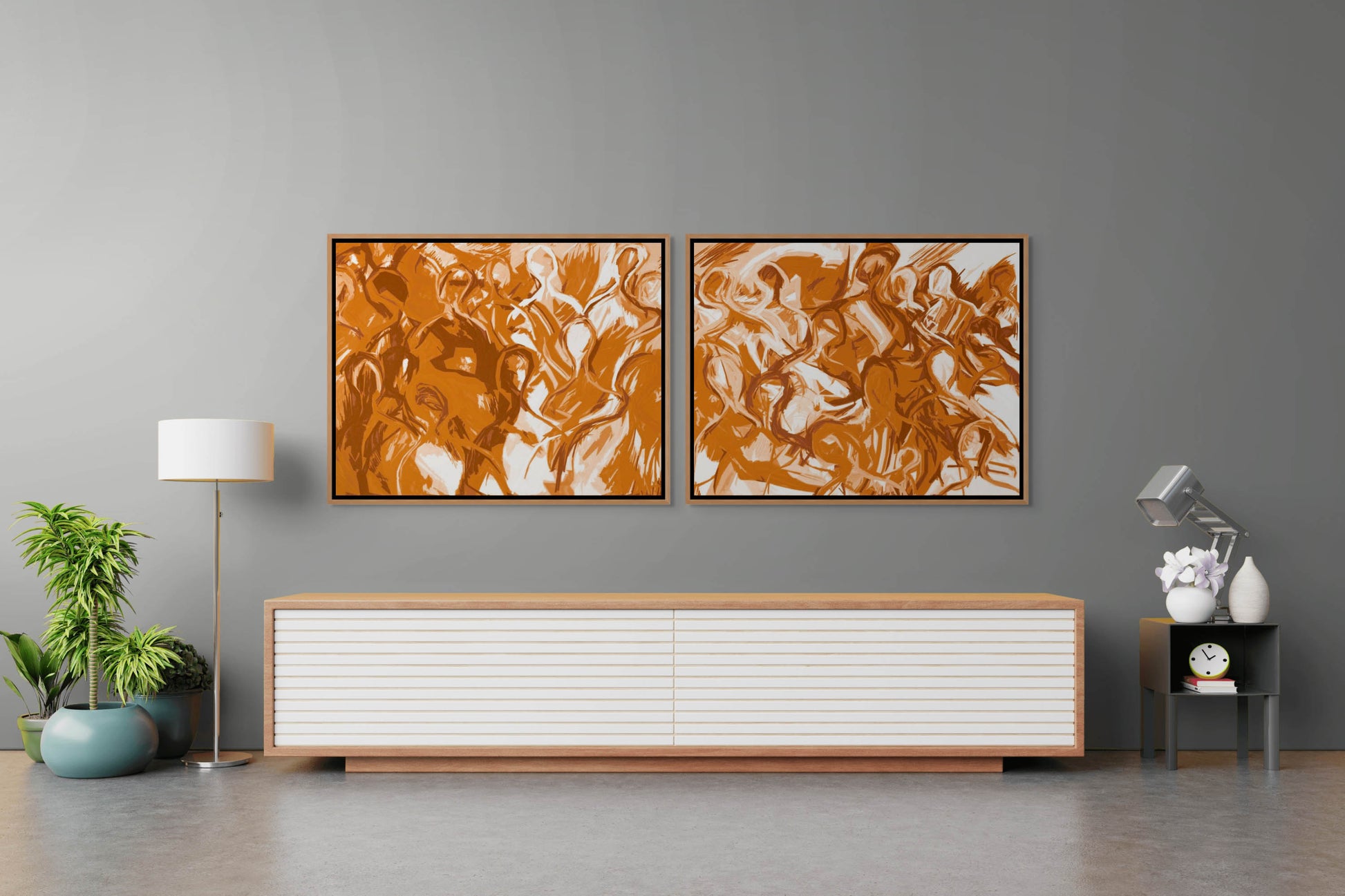 In a modern living room, two We Are All Connected abstract orange canvases embellish a gray wall. Below, a sleek console table in white and wood holds a clock, lamp, and books. A potted plant and floor lamp flank the space, creating an inviting ambiance.