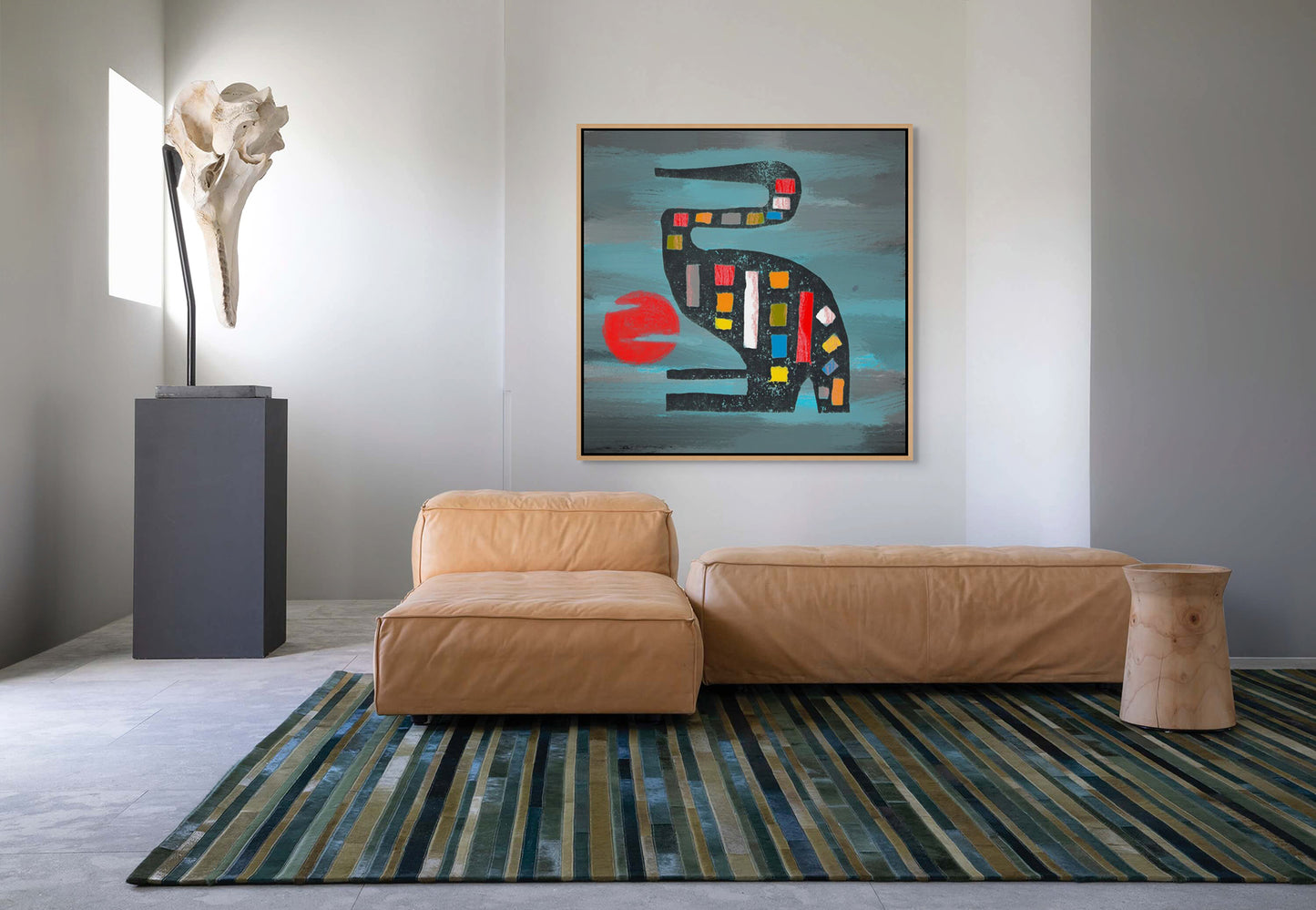 A modern living room with a tan leather sofa, wooden side table, and green-striped rug features the Seated Crane - Contemporary African Design Canvas Art Print created using Eco-Solvent inks. A sculpture near the window brings in an African art vibe.